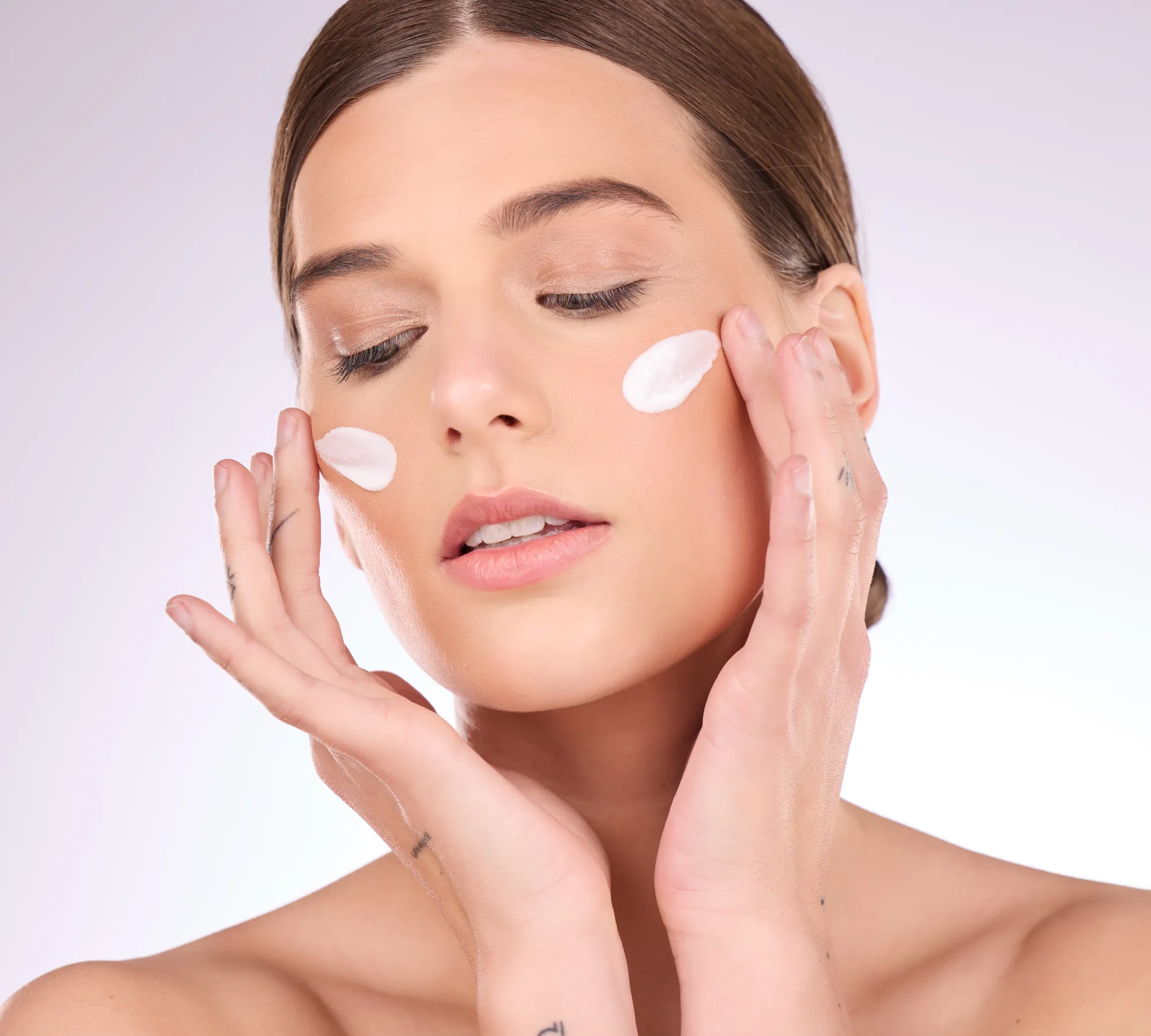A beauty photo of a young woman with facial cream on her cheeks.